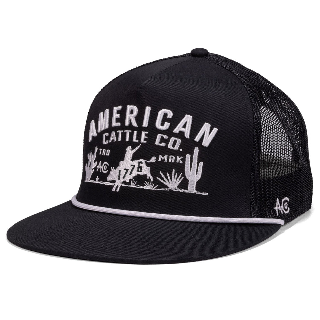 The American Cattle Co 8-Second Hat is a black mesh-back flatbill featuring white “American Cattle Co.” embroidery above a cowboy on horseback with cacti, plus a small "AC" embroidered on the side.