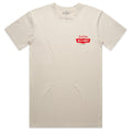The All Grit Tee by American Cattle Co is a beige, athletic-fit, short-sleeve crew neck shirt made from premium cotton. It features small red and black 