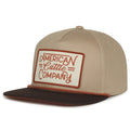 The Billboard Script Hat by Rural Cloth features a beige and brown design, flat visor, and a front patch with 