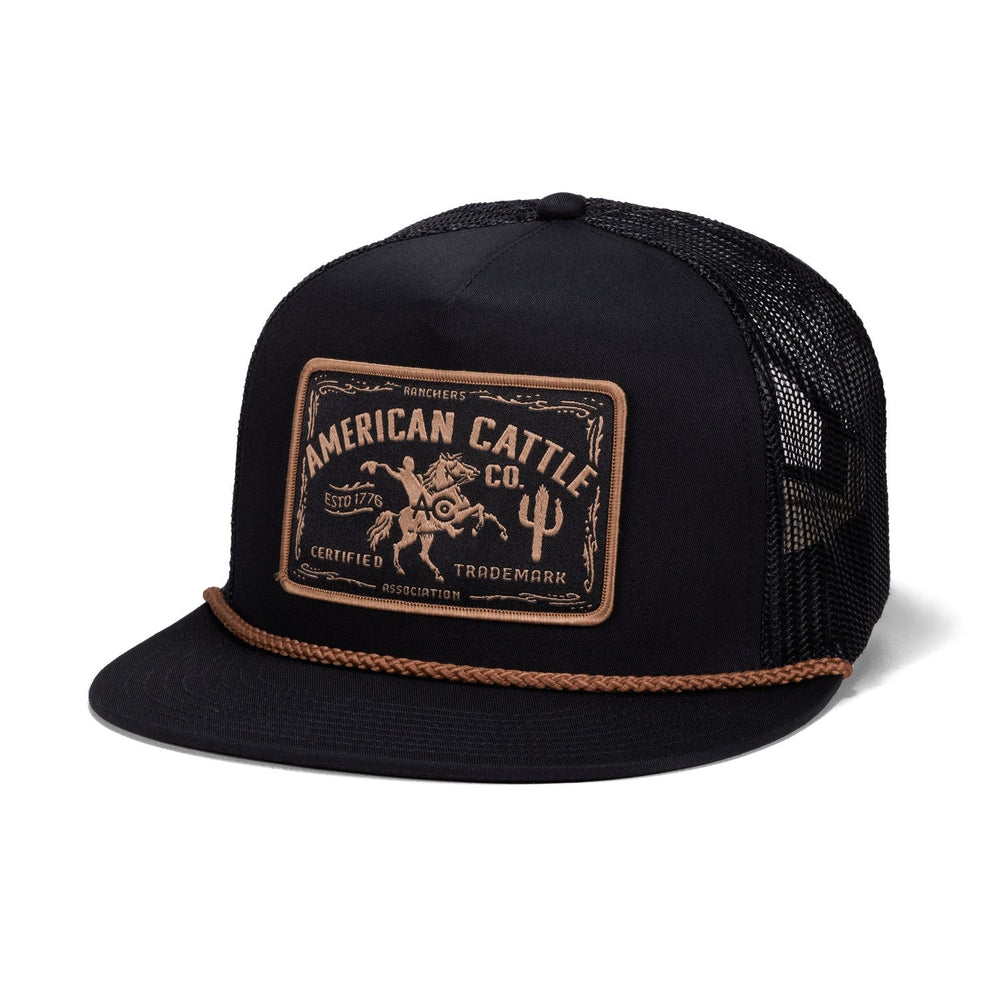 The Bucking Horse Hat by Rural Cloth is a black mesh trucker hat featuring a flat brim, brown rope detail, and a front patch with "American Cattle Co." alongside illustrations of a cowboy, bull, and cactus in brown—blending classic ranch style with modern flair.