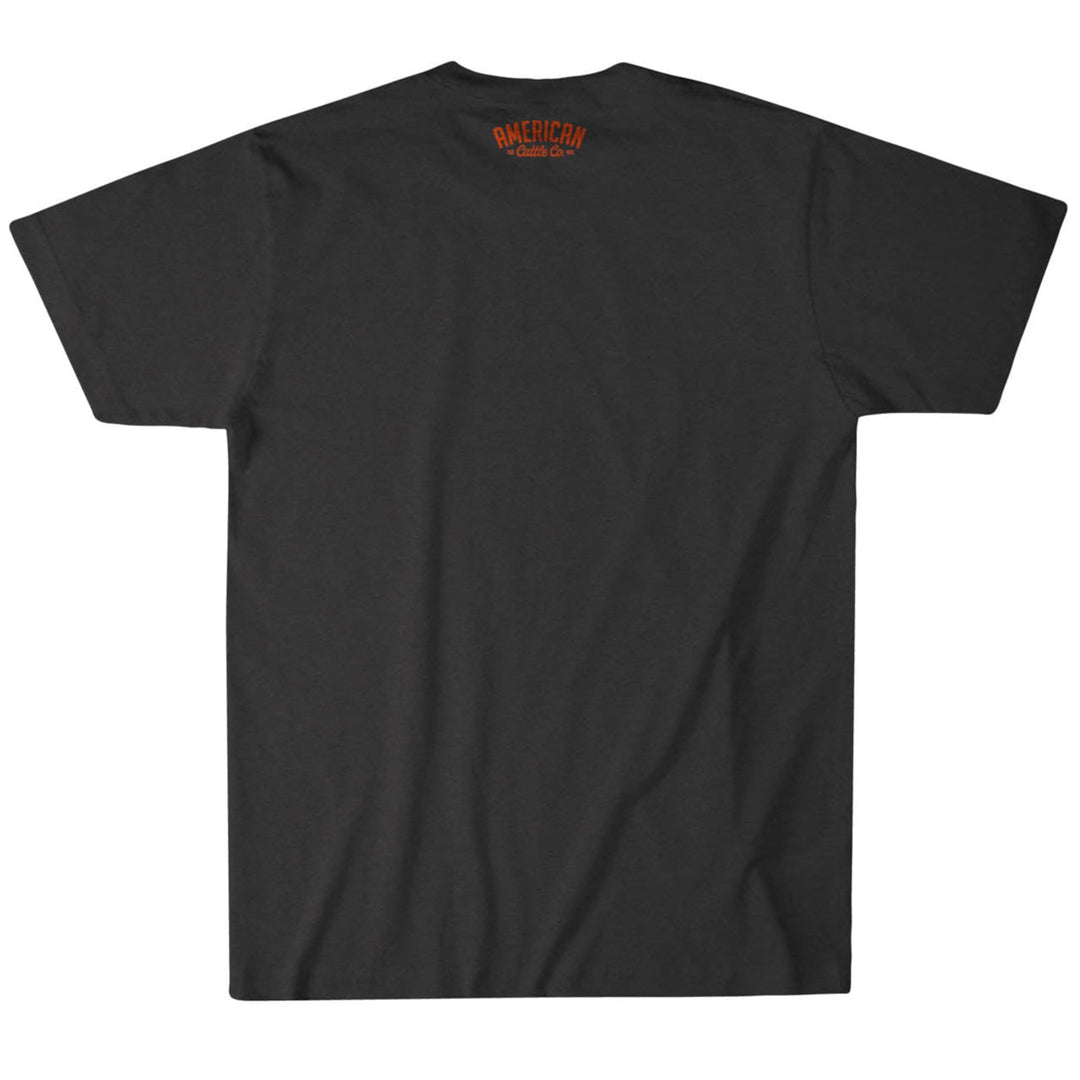 The Bull Spurs Icon Tee is displayed from the back, featuring a minimalist design with only small orange “AMERICAN CLASSIC CO.” text near the neckline. Inspired by rural American heritage, this black short-sleeve t-shirt maintains a clean look with no visible logos or designs aside from the subtle orange detail by the collar.