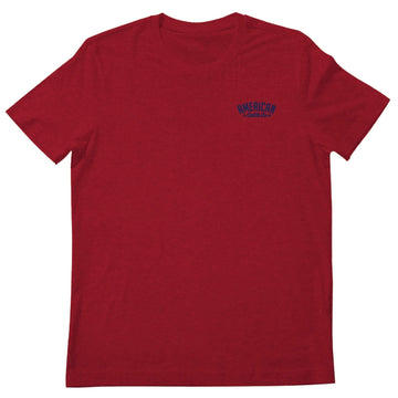 The Rural Cloth Cactus Tee is a plain red short-sleeve shirt with a small blue "AMERICAN Classic Co." logo on the upper left chest, laid flat on a white background and inspired by classic American cattle ranch heritage.