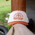 The Certified Ranchers Association Hat by Rural Cloth features white and orange embroidery with 