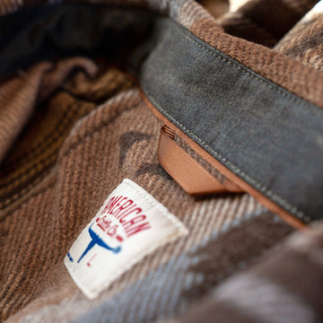 Inside collar of the Desperado Polar Fleece in Brown showing the leather hang tab, suede collar stand and neck label.