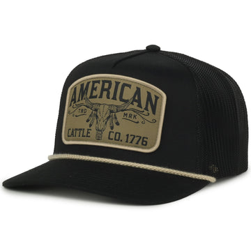 The American Cattle Co Headdress Hat in black features a beige patch with a longhorn skull, "American Cattle Co. 1776" text, and a beige rope across the brim—ideal for showcasing classic American grit.