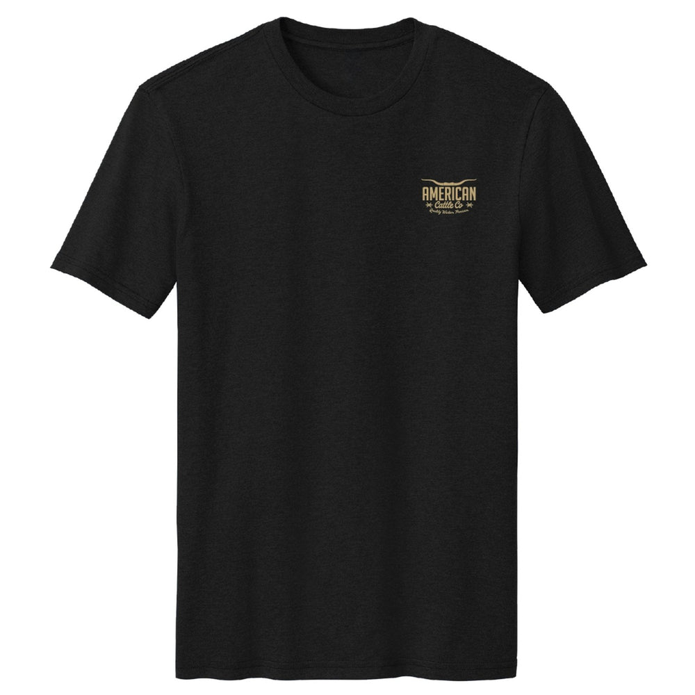 The Heritage Tee by American Cattle Co is a black short-sleeve shirt with a vintage "American Motorcycles" logo on the left chest, shown on a plain white background.