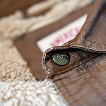 AC logo snap on the brown collar, with sherpa lining, on the Homestead Jacket in Buck.