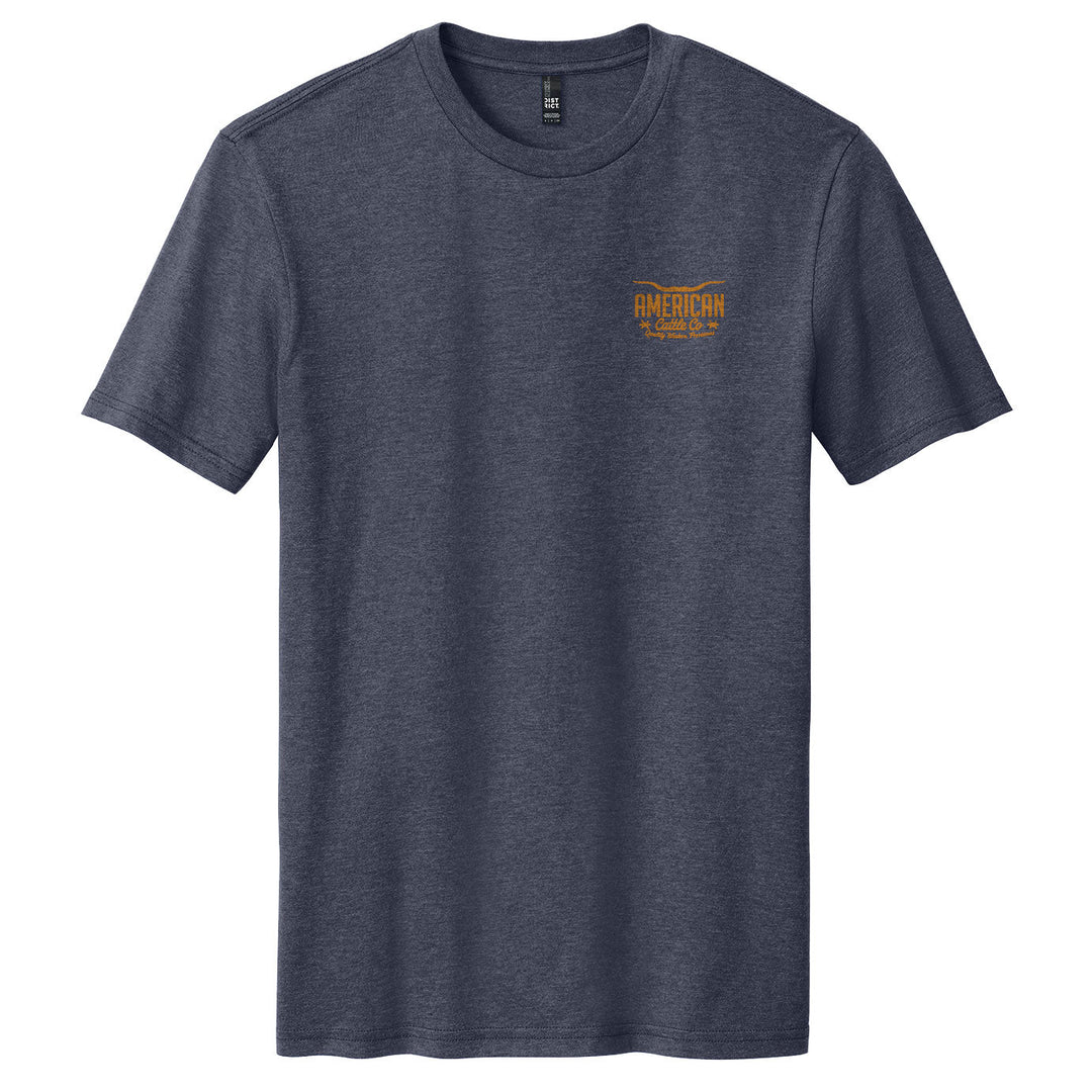 A heather navy Label Tee by American Cattle Co with short sleeves, featuring a small orange logo on the left chest, is laid flat on a white background.