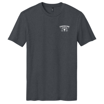 The Liberty Buck Tee by American Cattle Co is a plain dark gray western t-shirt with a small white "American Garage" text and crossed wrenches graphic on the left chest, designed in the classic American Cattle Co style.