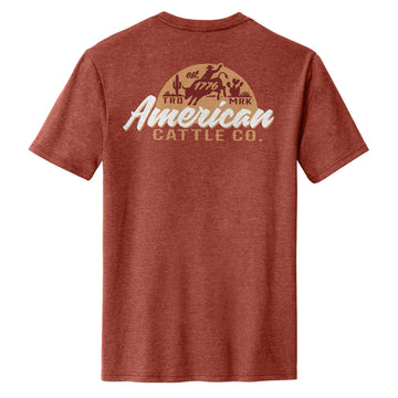 The Liberty Buck Tee by American Cattle Co comes in Heather Russet, featuring a bold cowboy, cattle, and cacti graphic on the back with "American Cattle Co.," "est. 1776," and "TRD MRK"—true Western style for range lovers.