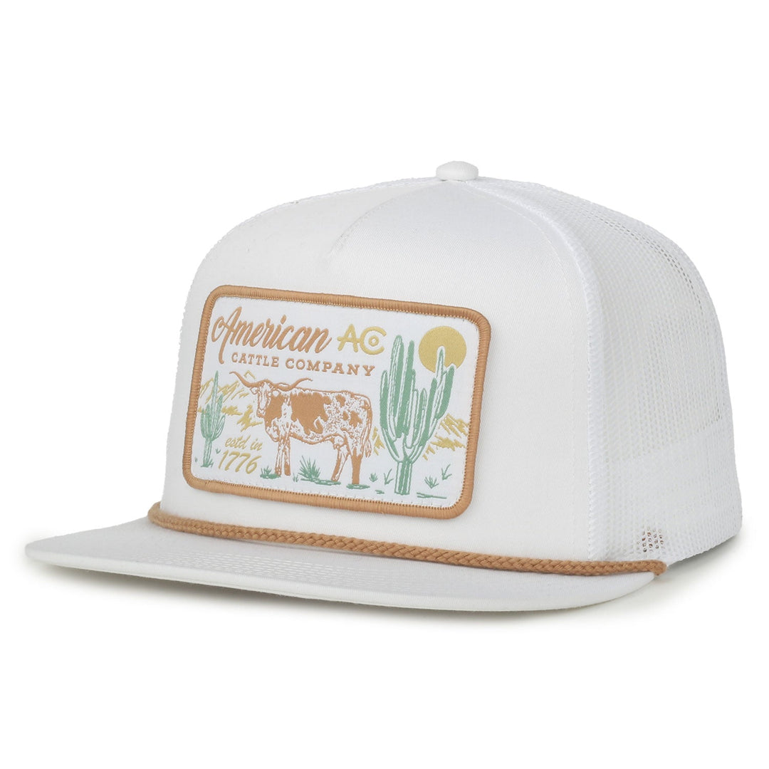 The American Cattle Co On the Range Hat is a white mesh-back snapback with a flat brim, featuring a patch with cow, cactus, and sun designs plus "American AC Cattle Company, Est. 1776" in tan, green, and brown embroidery.