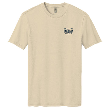 The American Cattle Co Quality Western Tee is a cream cotton blend with short sleeves, a classic crew neck, and a small "AMERICAN" logo on the left chest.