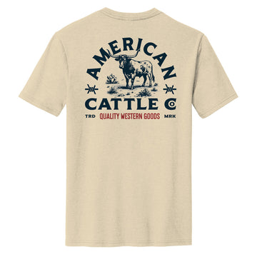 The Quality Western Tee by American Cattle Co features a cream cotton blend with a bold blue and red steer, desert plants, and “Quality Western Goods” print on the back—a perfect Western shirt for any wardrobe.