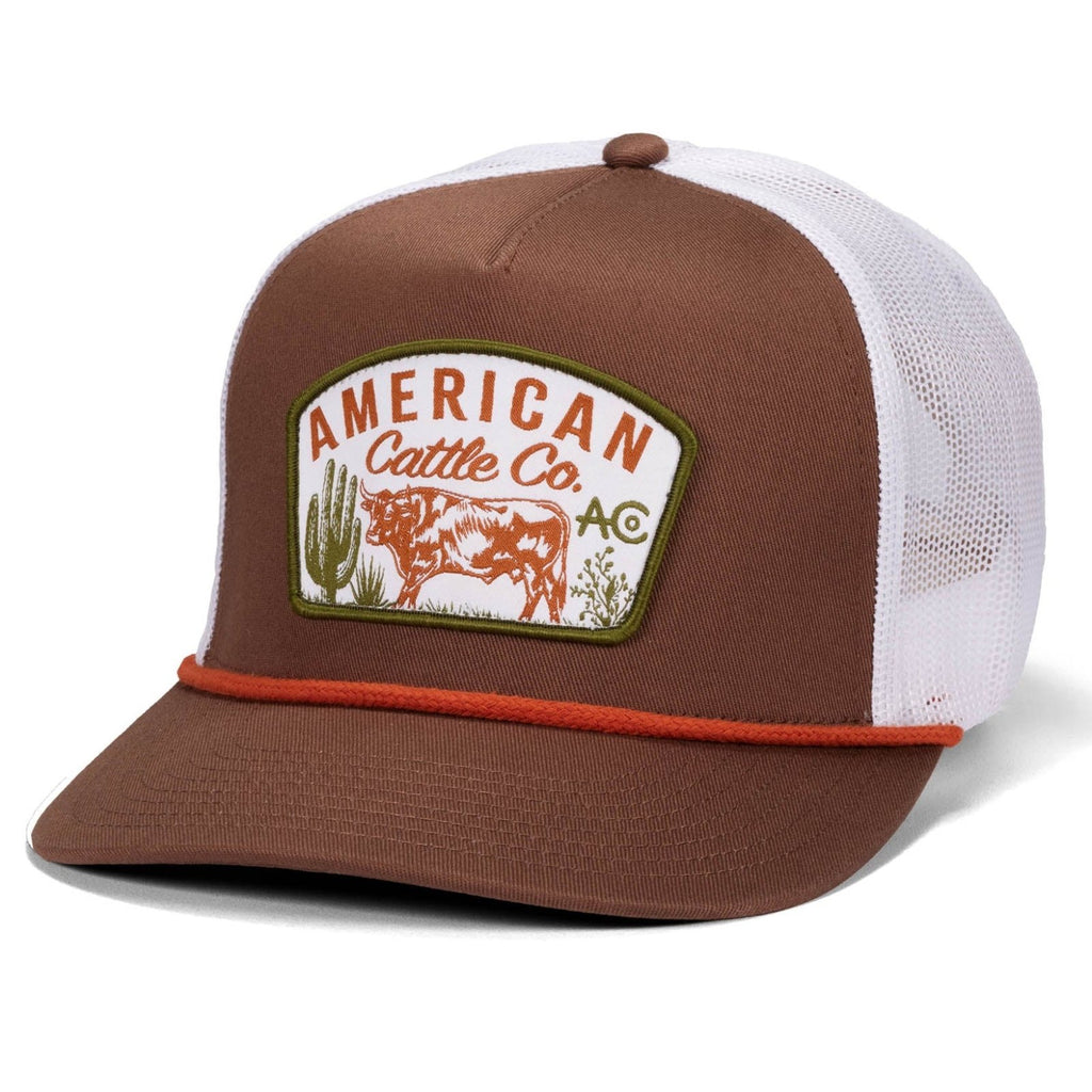 The Range Grazer Hat by Rural Cloth features a brown and white design, red rope detail, front patch with cow, cacti, and hills illustration, and an adjustable snapback for a perfect fit.