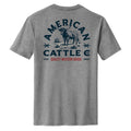 The Range King Tee by American Cattle Co is a heather gray shirt with a bold western back graphic featuring a blue longhorn bull, “American Cattle Co,” and “Quality Western Goods” in red accents and decorative details.