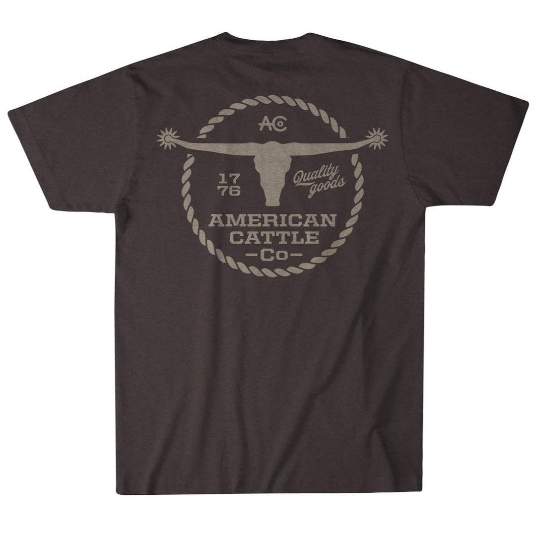 The Roper Tee by American Cattle Co is a dark brown vintage t-shirt with a bold back graphic of a longhorn skull, "AC," "1776," "Quality goods," and "American Cattle Co." inside a rope border—ideal for classic Western style fans.