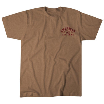 The Shadowhorn Tee by American Cattle Co is a plain brown short-sleeve western shirt featuring small red "American Cattle Co" text on the left chest, shown on a white background.
