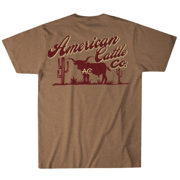 The Shadowhorn Tee by American Cattle Co features a gold heather short-sleeve design with a bold maroon bull, two cacti, and "American Cattle Co." text with "AC" initials—ideal for any cattleman’s collection.