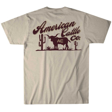 The cream Shadowhorn Tee from American Cattle Co features a bold longhorn silhouette between two cacti, with "American Cattle Co." and "AC" in dark brown, encapsulating the spirit of the cattleman's code.