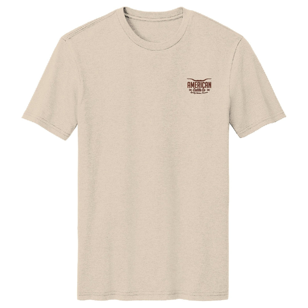 The Stampede Tee by American Cattle Co is a classic fit, plain beige shirt in a soft cotton blend. It features a small brown and red "American Muscle" logo on the left chest and is shown on a white background.