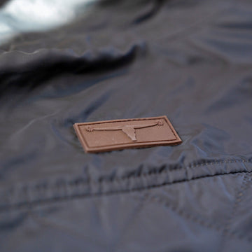 Leather longhorn logo patch on the quilted shell of the Sunday Jacket in Thundercloud.