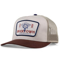 The Outlaw GOAT Hat by Rural Cloth is a beige and brown western hat with a mesh back, front patch reading “Est 2022 Bucktown Stephenville, TX,” and features an illustrated cowboy in a hat and bandana.