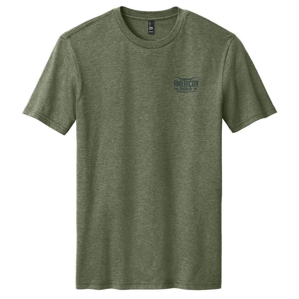 A heathered olive green Waterline Tee by American Cattle Co is shown on a white background, featuring "AMERICAN EAGLE" text and a small cattleman’s life graphic printed on the left chest.