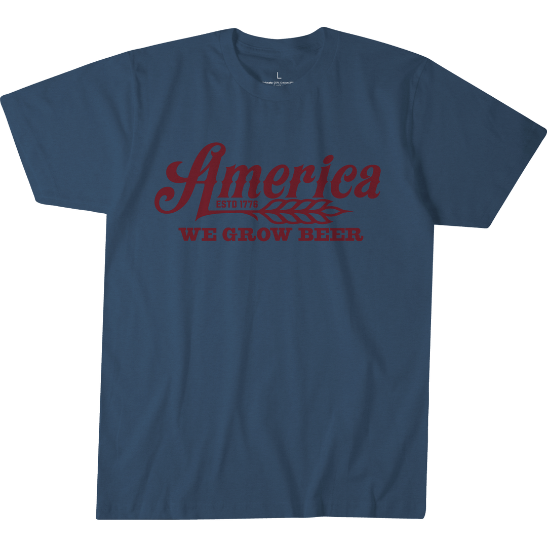 The We Grow Beer Tee-Heather Blue by Rural Cloth is a premium athletic-fit t-shirt in heather blue, featuring dark red "America ESTD 1776" above a wheat stalk and "WE GROW BEER" below. Proudly made in the USA.