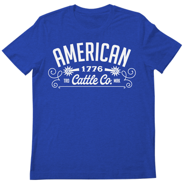 The American Cattle Co Western Tee is a blue shirt with "AMERICAN 1776 Cattle Co. TRD MRK" in white and decorative flourishes, celebrating classic American cattle heritage.