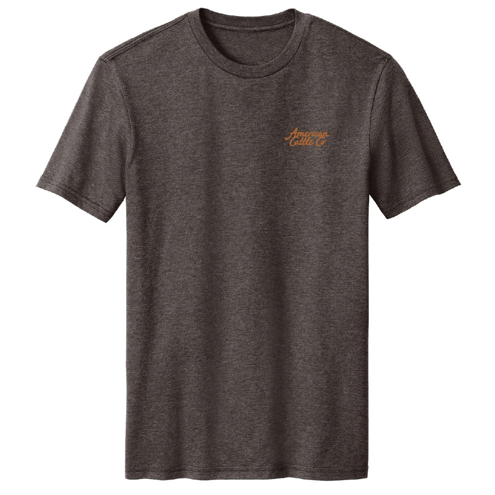 The Workhorse Tee by American Cattle Co is a vintage-style, plain dark gray short-sleeve shirt with “American Cattle Co” in small orange script on the left chest—perfect for everyday wear.