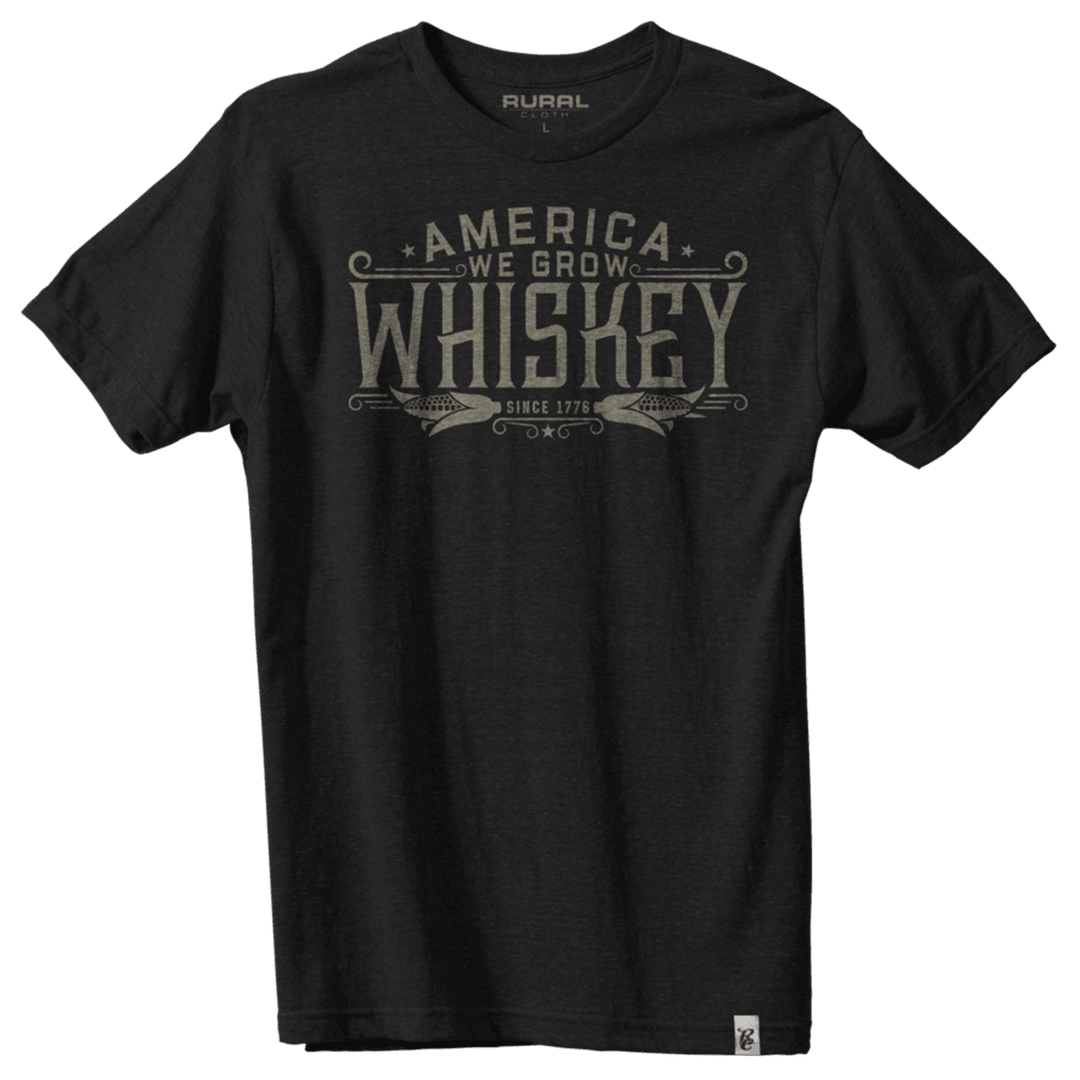 The Rural Cloth America We Grow Whiskey Tee is a black shirt with a modern athletic fit, featuring "America We Grow Whiskey Since 1776" in bold, vintage-style lettering across the chest.