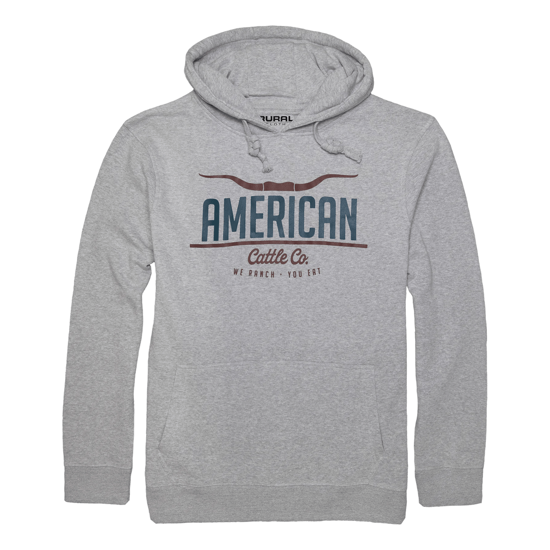 The American Cattle Co Pullover-Athletic Gray features a light gray hoodie with a front pocket and drawstring hood. "AMERICAN Cattle Co. WE RANCH • YOU EAT" is printed in bold blue and brown letters on the chest.