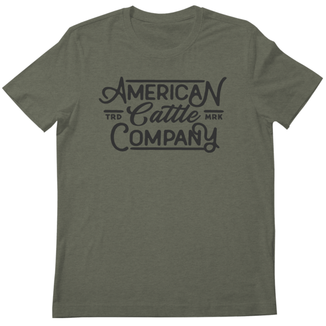 The Billboard Script Tee by American Cattle Co is an olive green shirt featuring "American Cattle Company" in bold script and "TRD MRK" by "Cattle," ideal for American ranching fans who appreciate classic style.