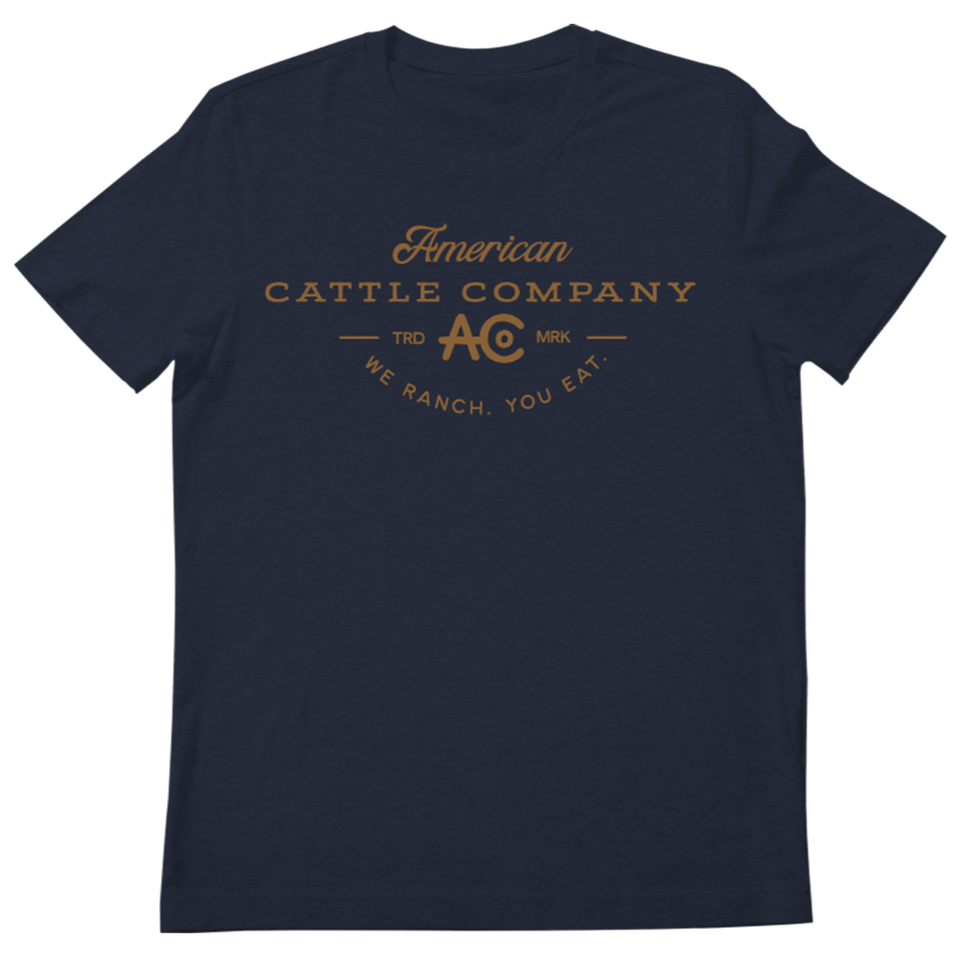 The Provider Tee-Heather Navy by Rural Cloth features "American Cattle Company," "AC," "TRD MRK," and "We ranch. You eat." in western tan font across the chest.