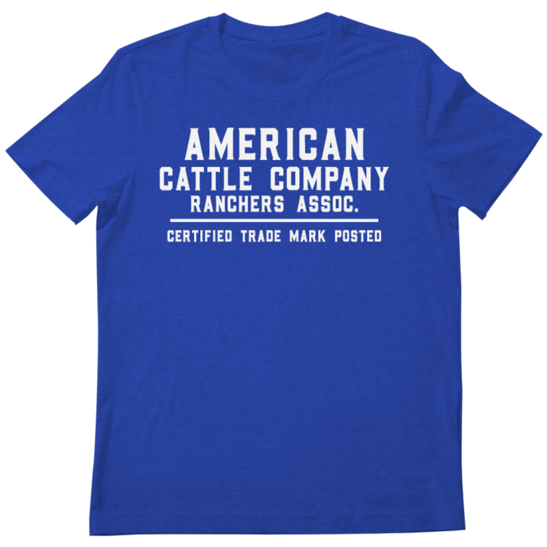 The Ranchers Association Tee by Rural Cloth features bold white block text—"AMERICAN CATTLE COMPANY Ranchers Assoc. CERTIFIED TRADE MARK POSTED"—on royal blue, perfect for fans of the ranching t-shirt trend.