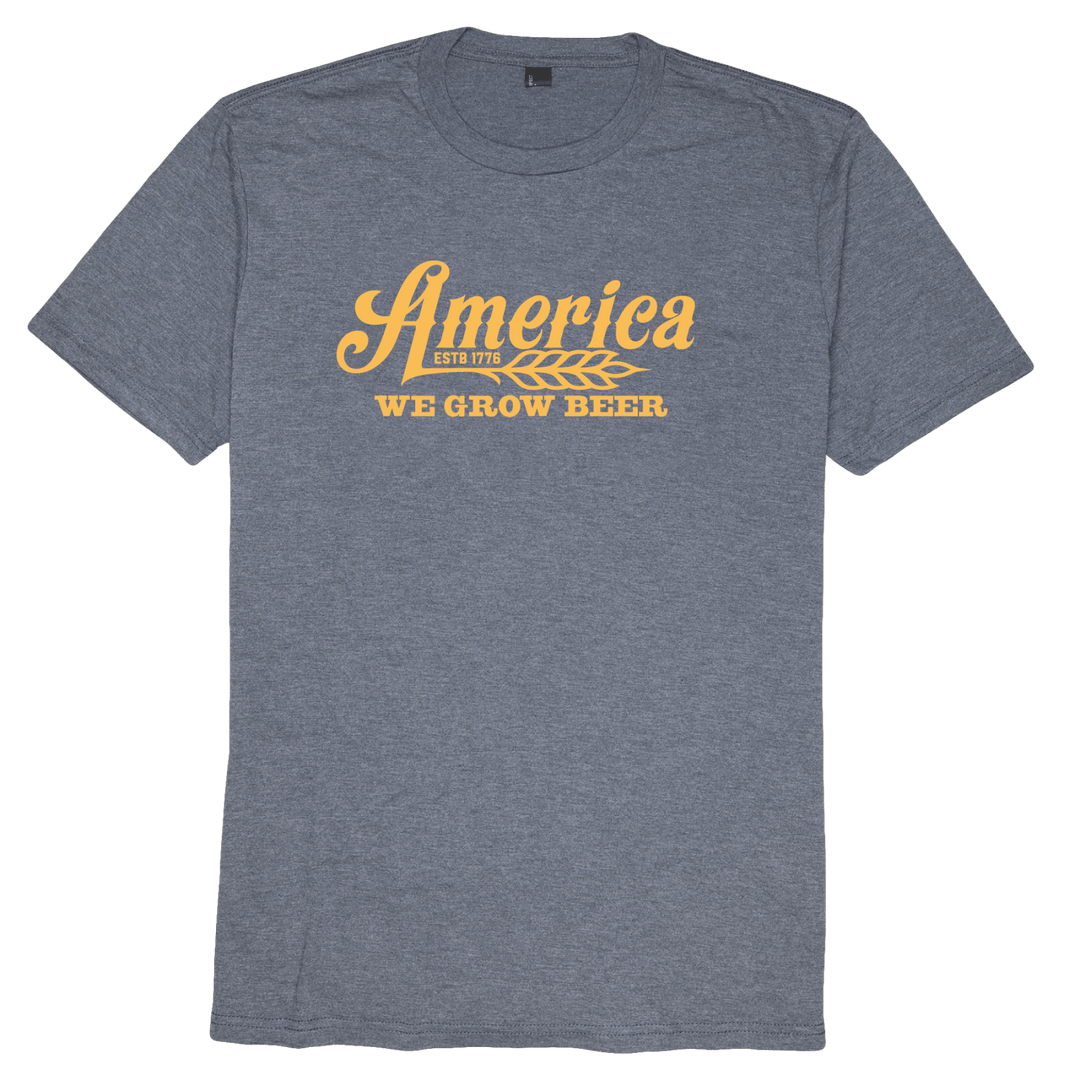 The Rural Cloth We Grow Beer-Navy Frost t-shirt features "America ESTD 1776 WE GROW BEER" in yellow with a wheat graphic below "America" on the front, style 110030046.